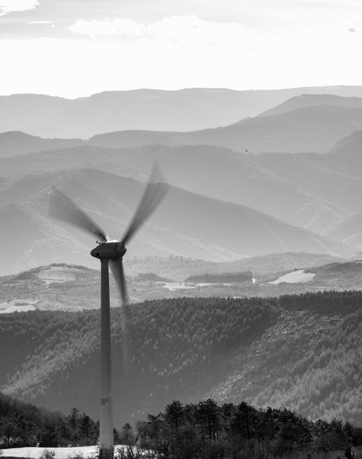 Éolienne en mouvement devant les reliefs, noir et blanc