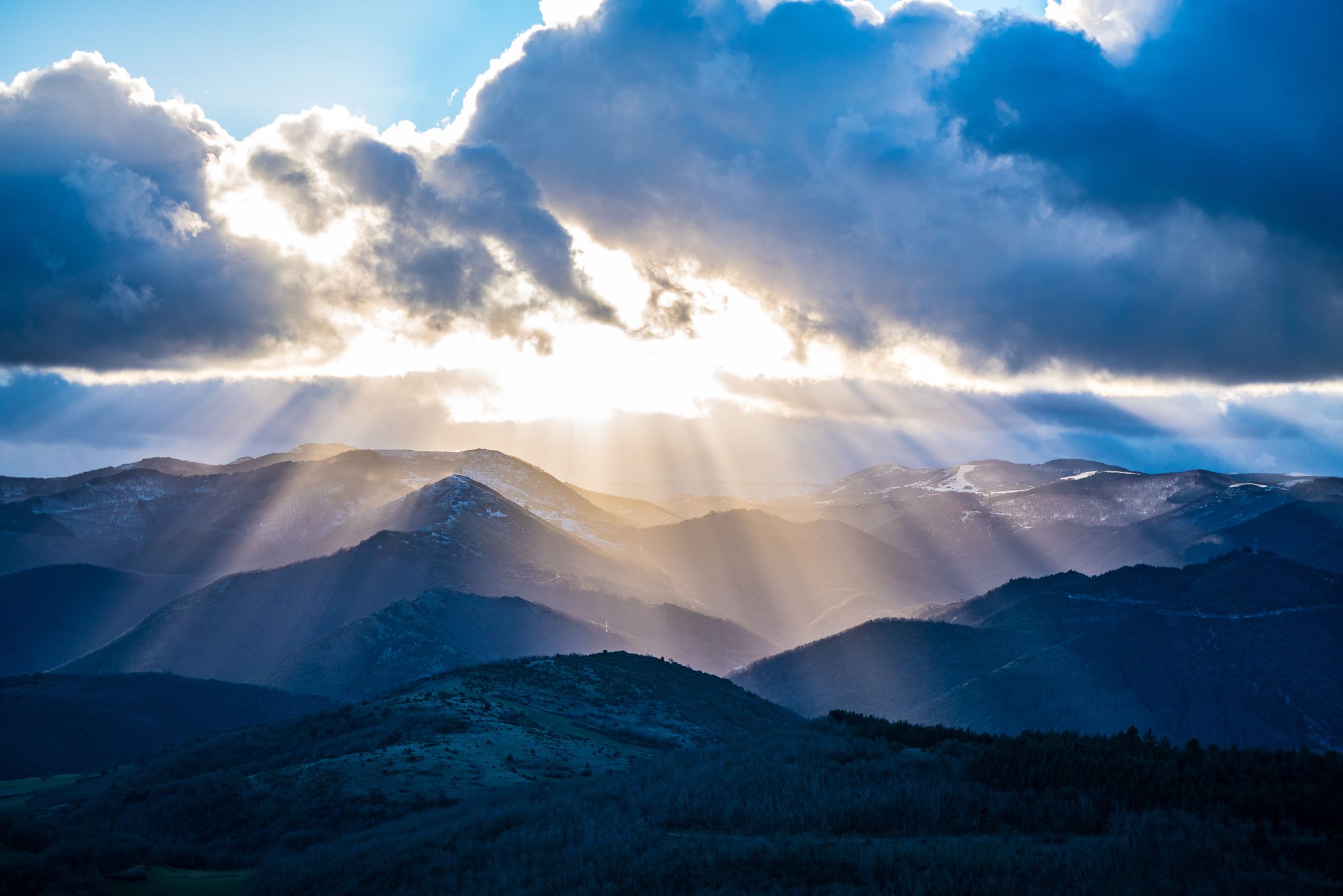 Rayons de soleil perçant les nuages au-dessus des monts d'Orb enneigés