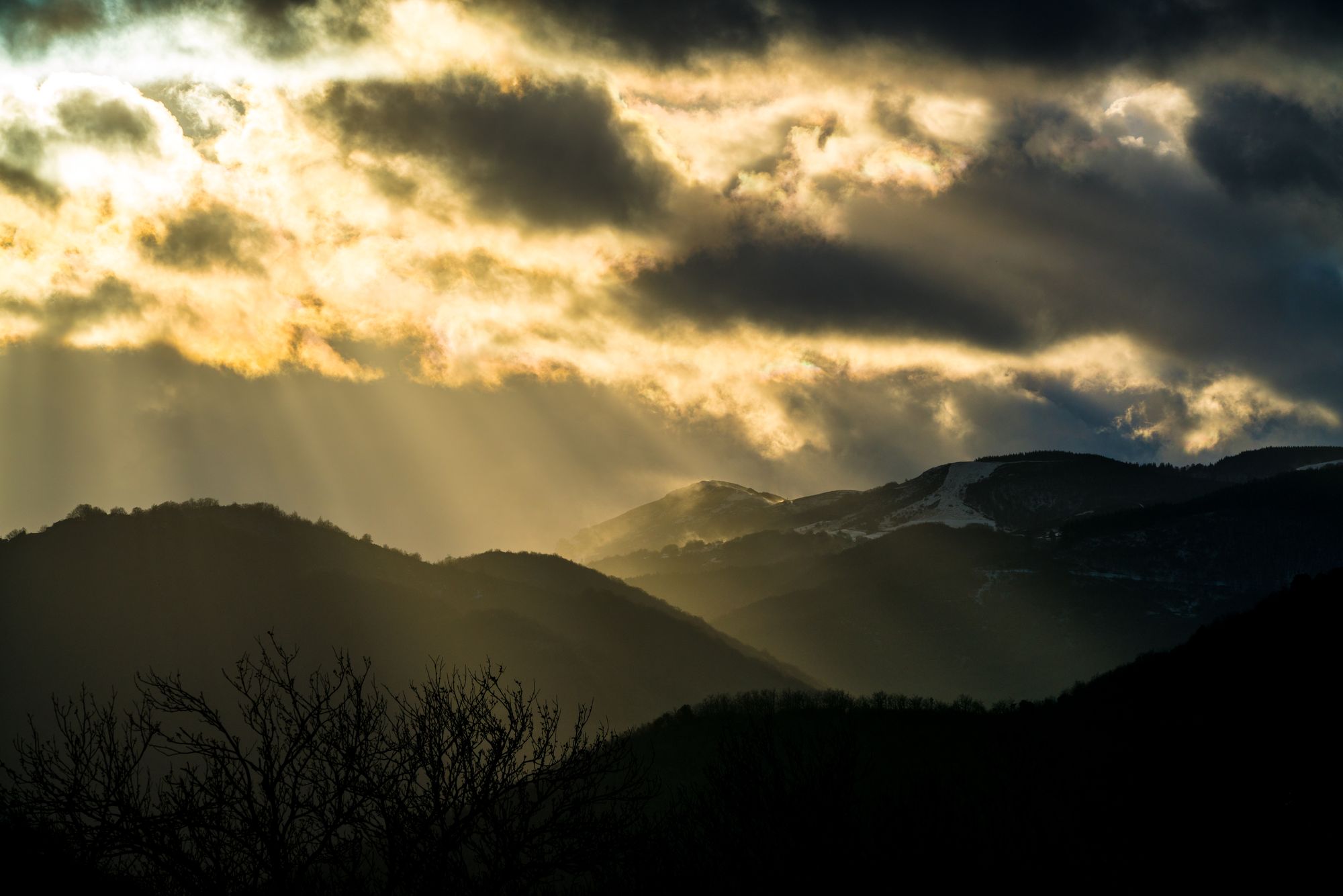Percée de lumière dorée à travers les nuages sur les montagnes